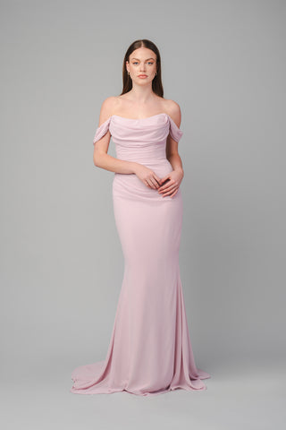 The Elea Dresses Marilyn dress is a fitted dress with a train. The bodice is pleated, and there are small pleated fabric details on the sleeves.