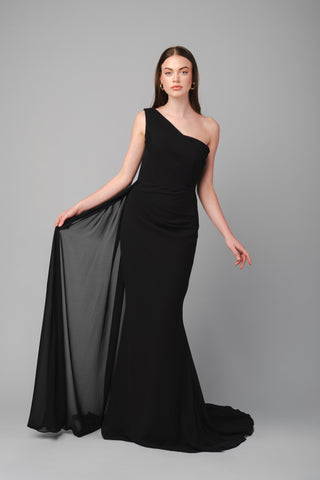 The Elea Dresses Selina dress in black is a one-shoulder fitted dress with a train. The top is pleated, and there is an additional pleated train on the side.