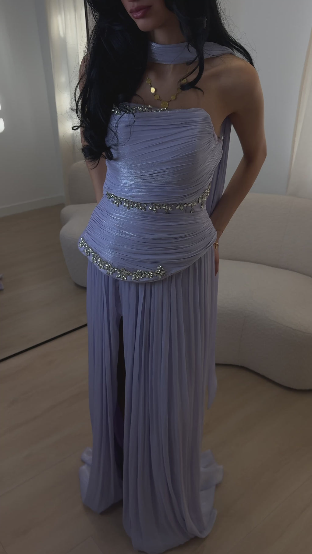 An elegant lavender evening gown "MILA" flows gently as it moves. The dress features soft, flowing pleats, a strapless design, and sparkling crystal embellishments that catch the light with every movement